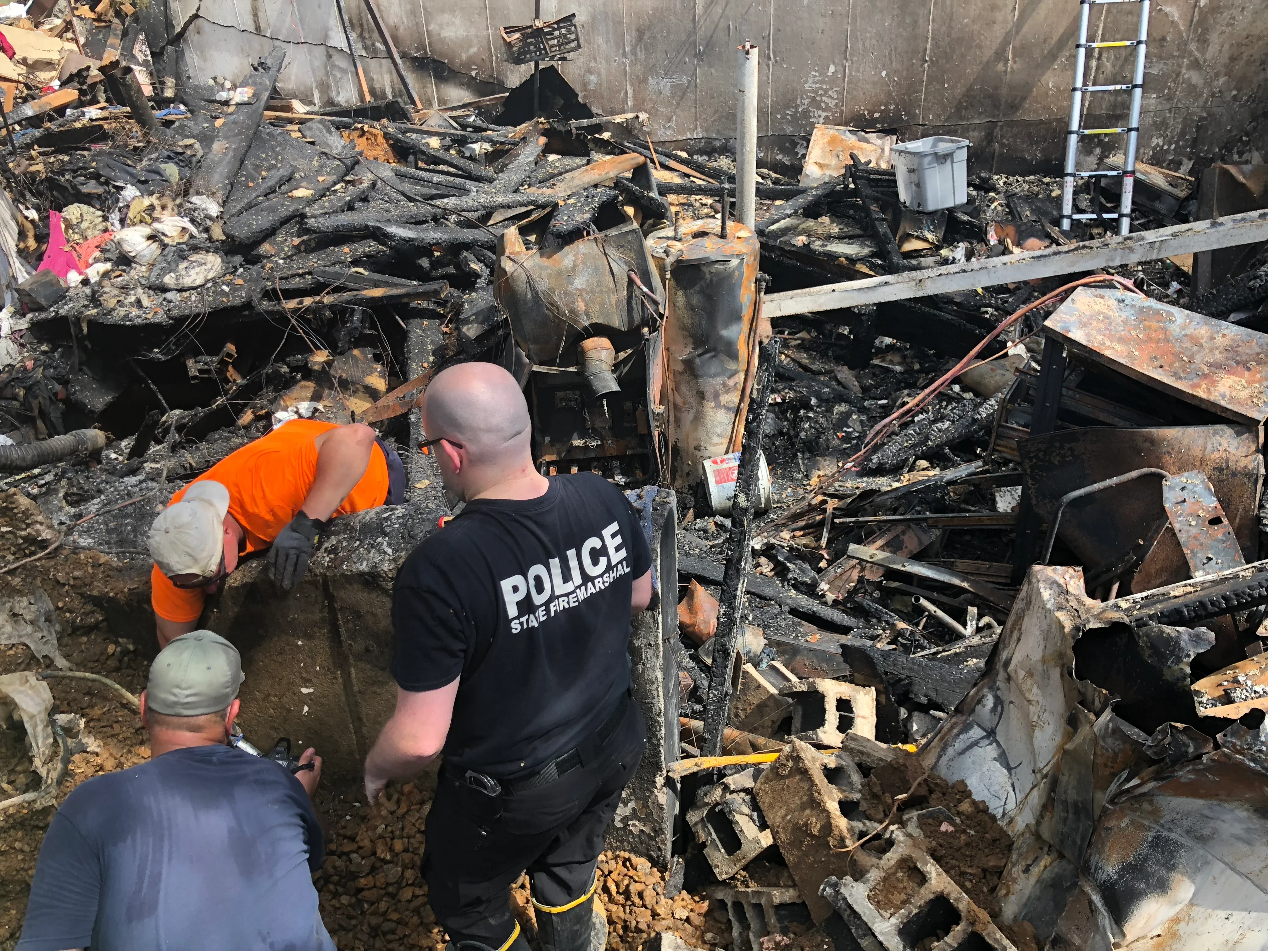 Fire-damaged structure debris removal with charred wood, metal, and concrete materials being cleared